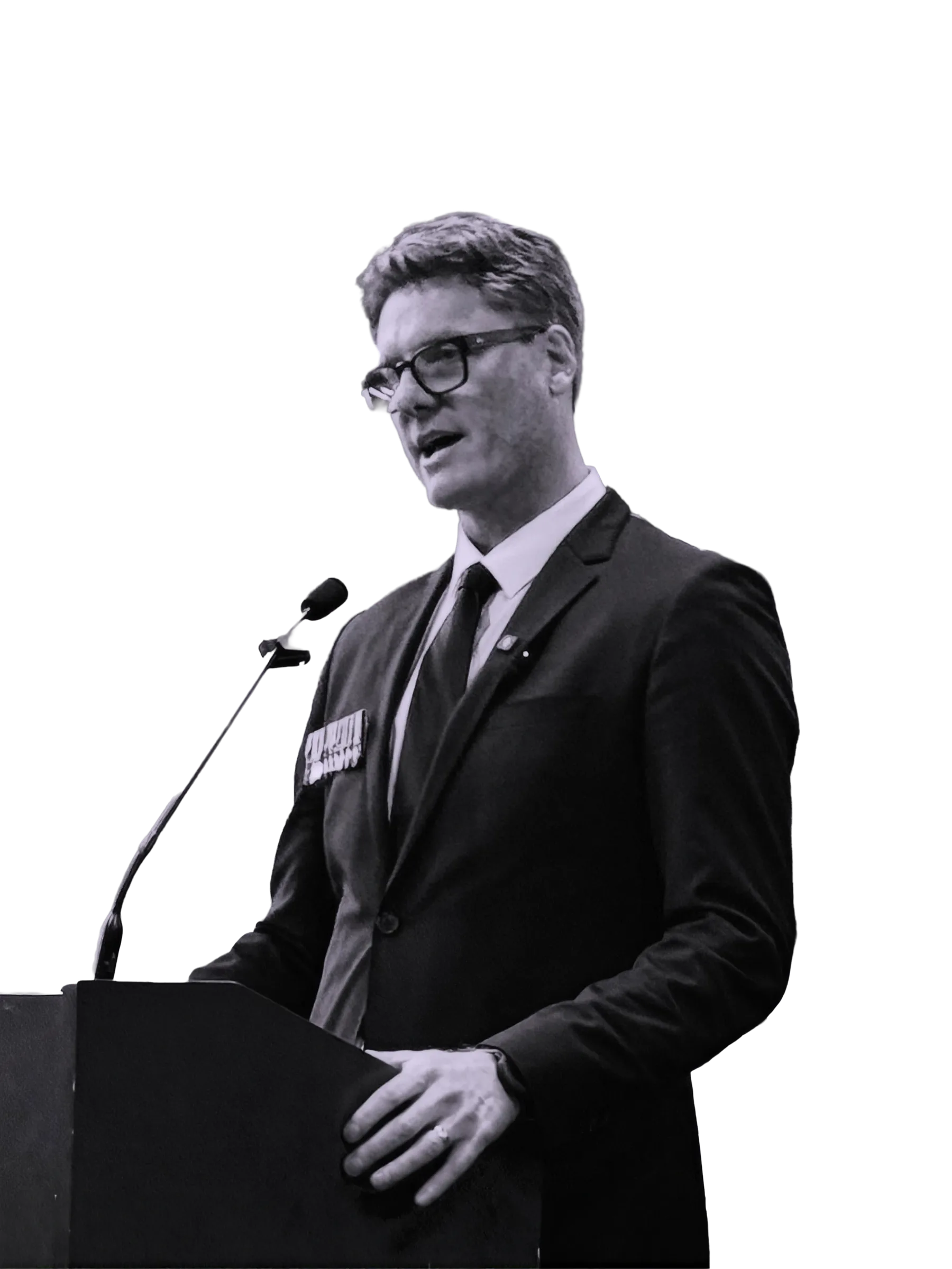Myles Pollard speaking at a lectern under stage lighting